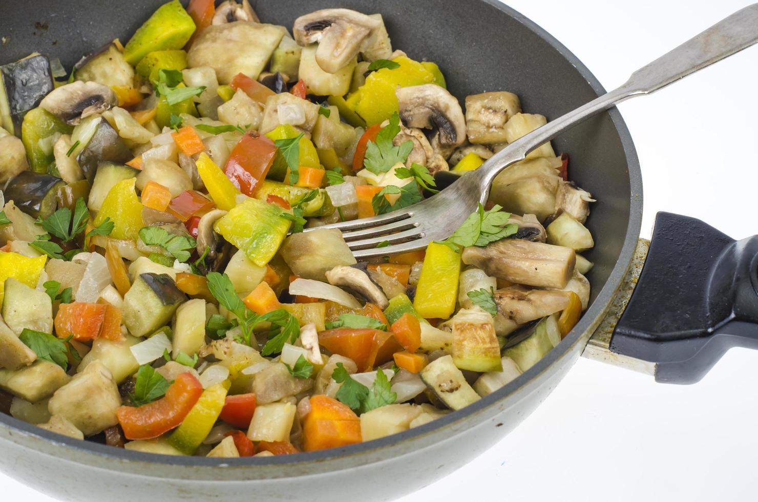 Frying pan with fried seasonal vegetables and mushrooms on white photo