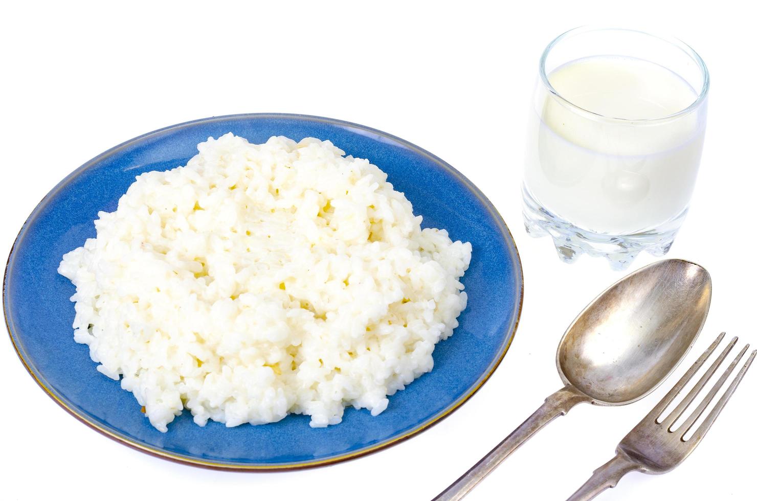 Deliciosas gachas de arroz con leche en placa azul sobre fondo blanco. foto