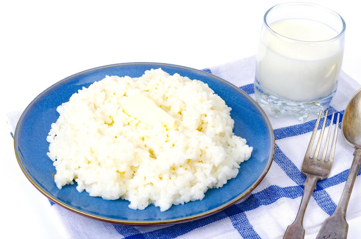 Deliciosas gachas de arroz con leche en placa azul sobre fondo blanco. foto