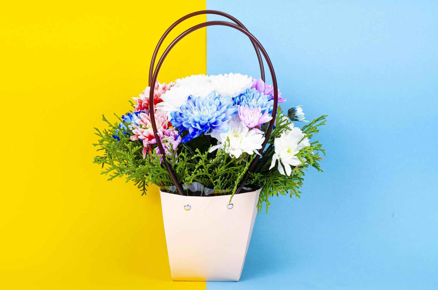 Decorative chrysanthemum flowers in basket on colored background. Studio Photo. photo