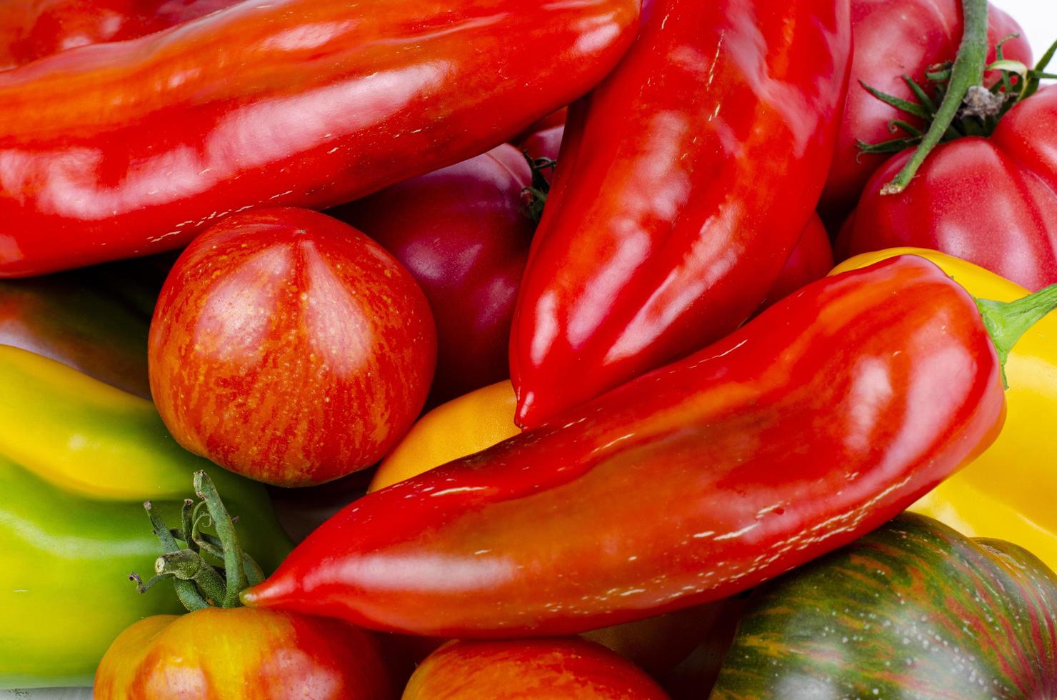 pimientos y tomates multicolores en la mesa de madera. foto de estudio.