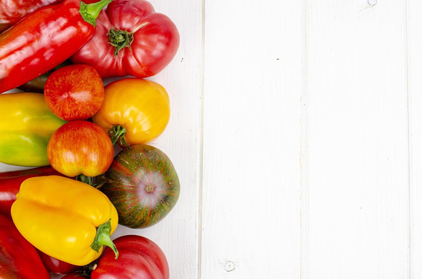 pimientos y tomates multicolores en la mesa de madera. foto de estudio.