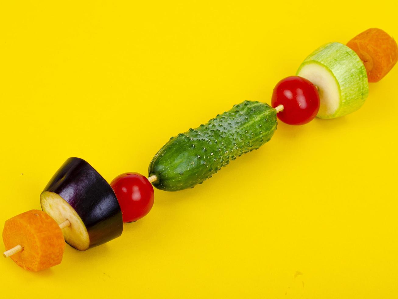 Organic fresh slises vegetables on wooden stick. Vegan or healthy food concept. Minimalistic still life on color bright background. photo