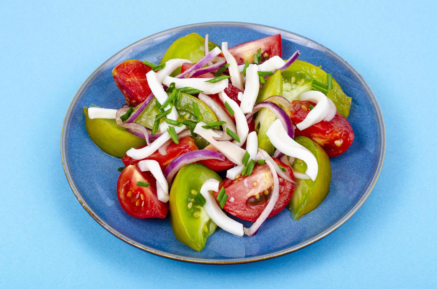 Ensalada de vegetales saludables con tomates y trozos de calamar. foto de estudio.