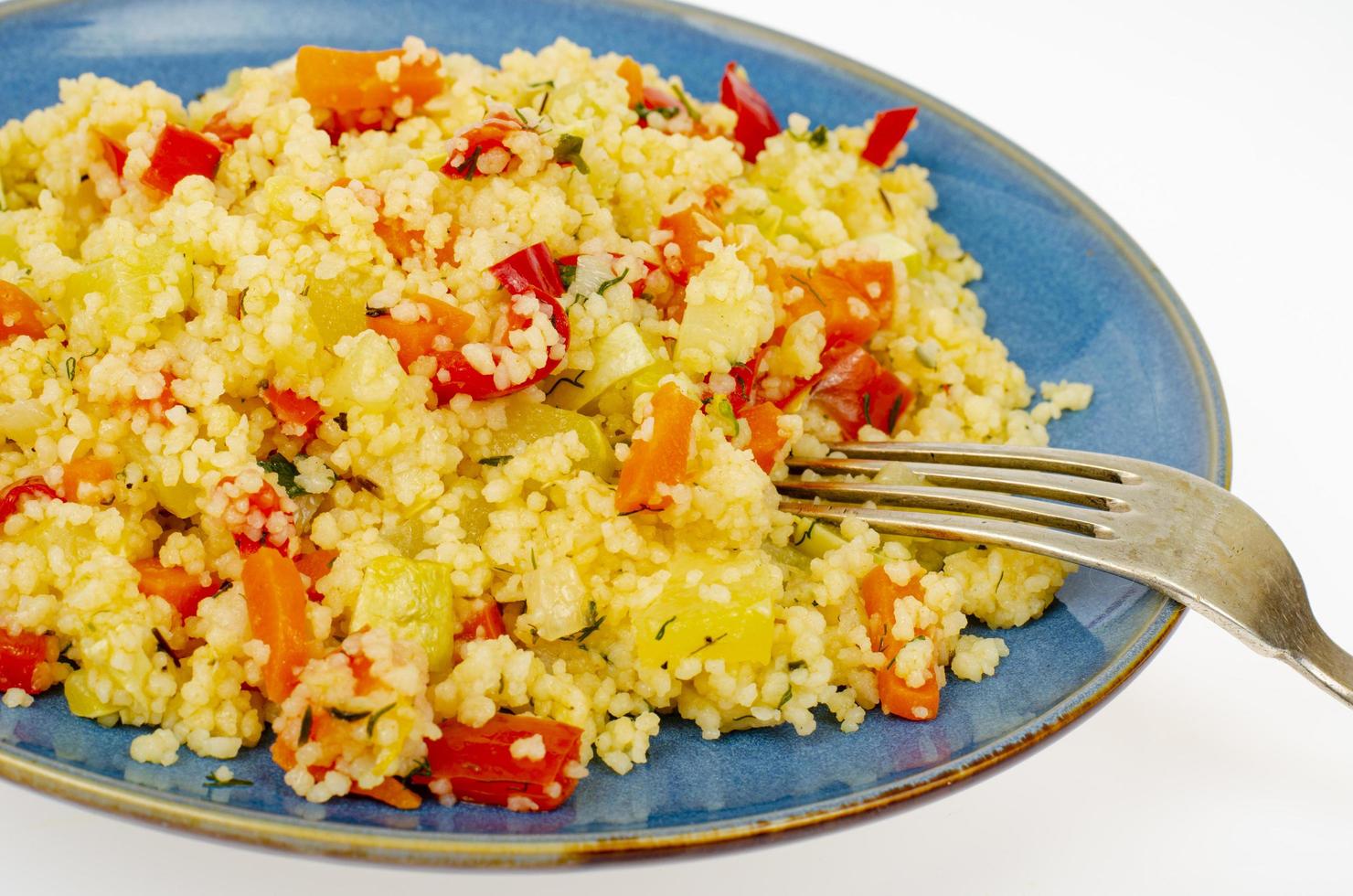 Vegetarian couscous pilaf with vegetables on blue plate. Studio Photo