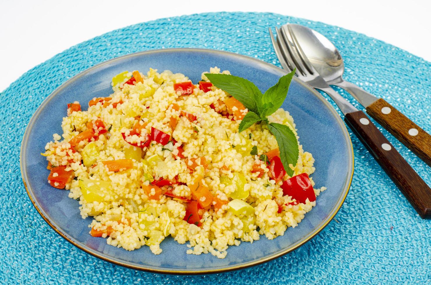 Pilaf de cuscús vegetariano con verduras en placa azul. foto de estudio