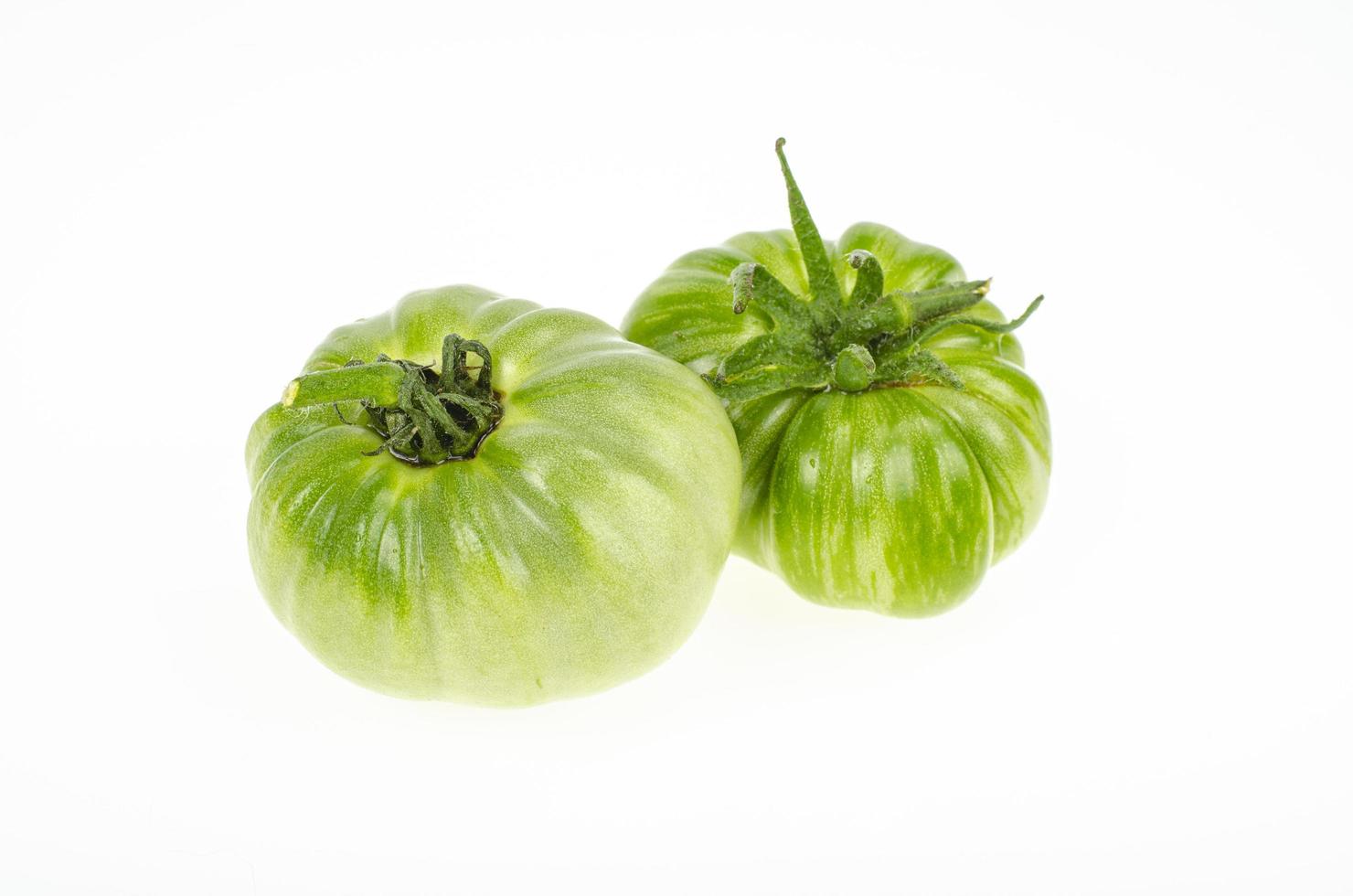 Two unripe green tomatoes isolated on white background. Studio Photo