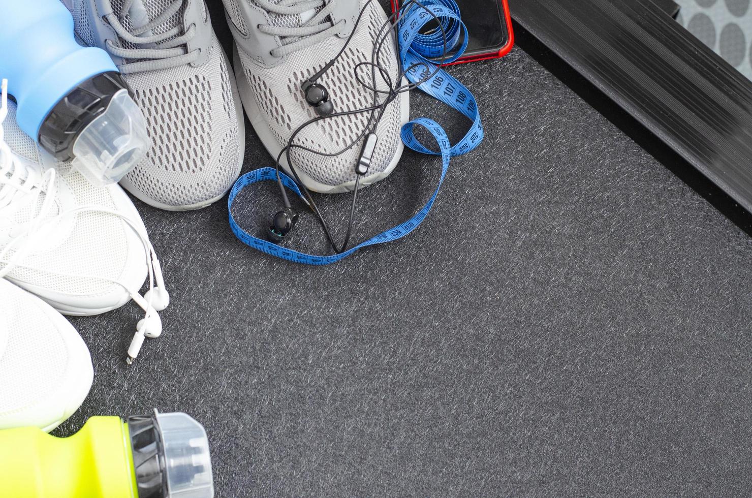 Running track with sneakers and bottle of water on black background. Exercise tools for health. Studio Photo