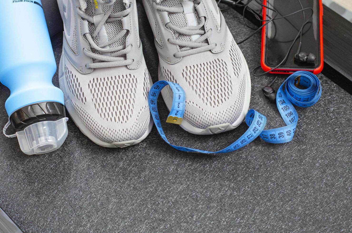 pista de atletismo con zapatillas y botella de agua sobre fondo negro. herramientas de ejercicio para la salud. foto de estudio