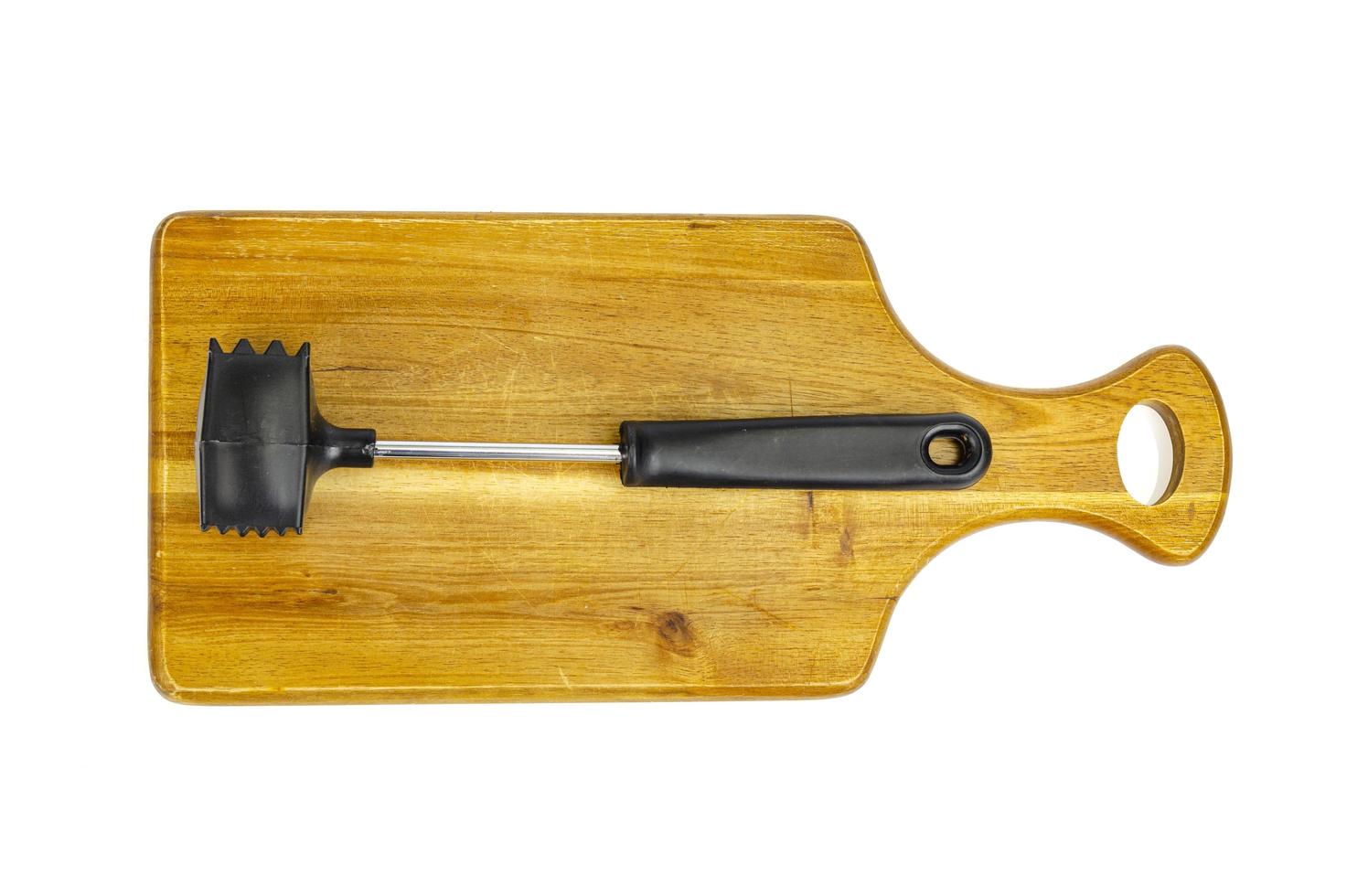 Kitchen hammer for meat on wooden cutting board. photo