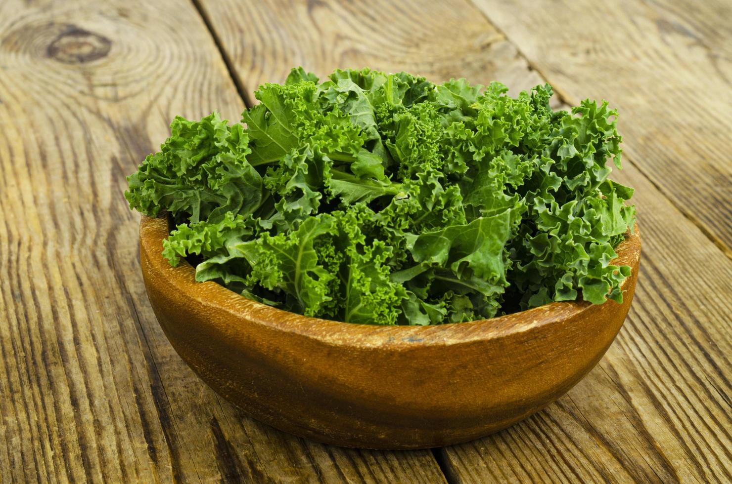 Fresh green sabellica leaves on wooden background, healthy organic food. photo