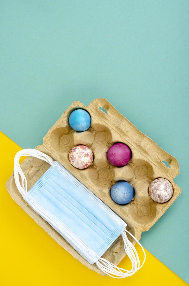 Concept of quarantine at Easter. Decorative eggs and white protective masks on bright background. Social distancing photo