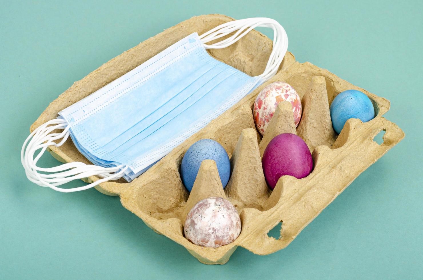 Concept of quarantine at Easter. Decorative eggs and white protective masks on bright background. Social distancing photo