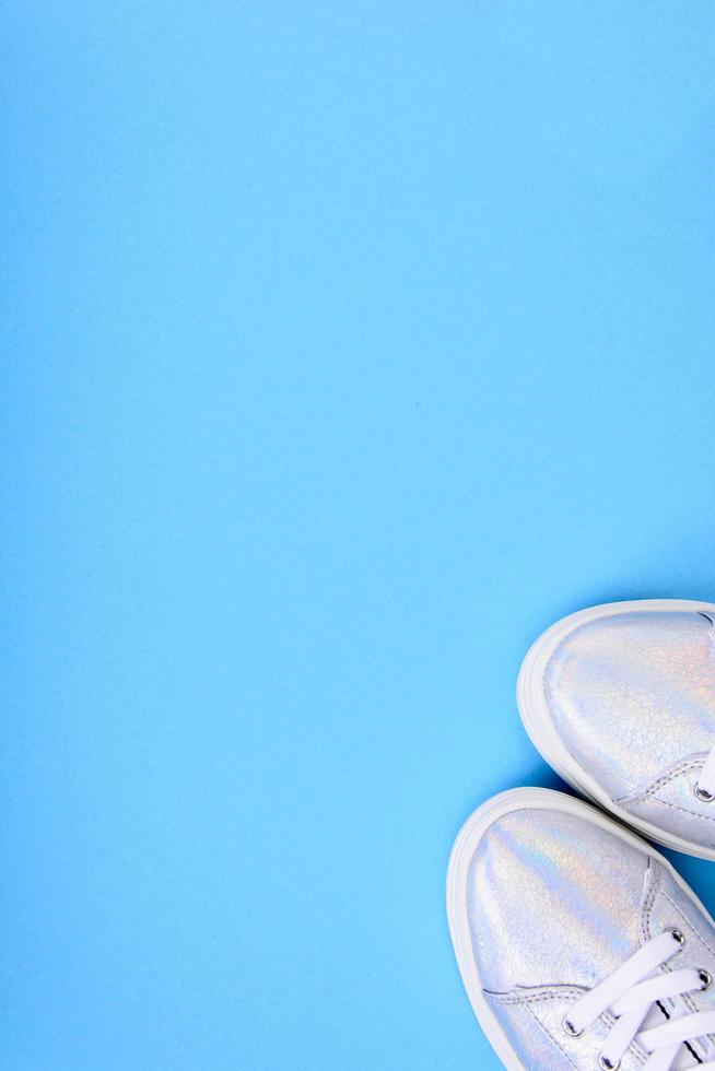 Zapatillas plateadas sobre un fondo azul con lugar para texto foto
