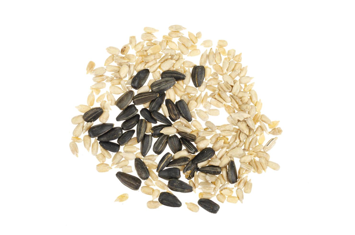 Peeled and in black shell sunflower seeds are frozen in air on white background. photo