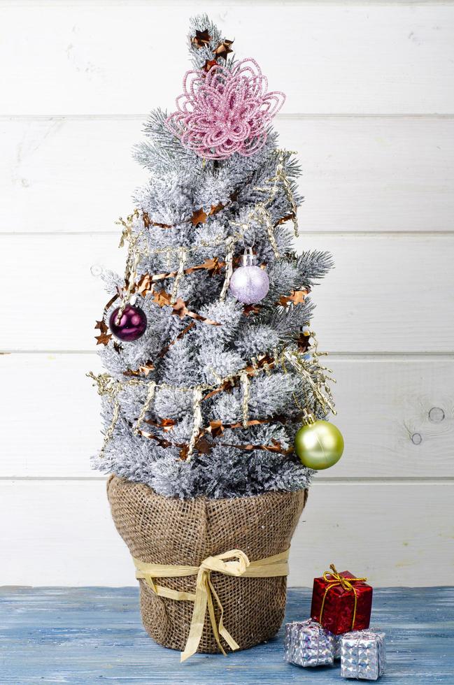 We celebrate Christmas and New Year. Small decorative Christmas tree decorated with balls and toys. Studio Photo. photo