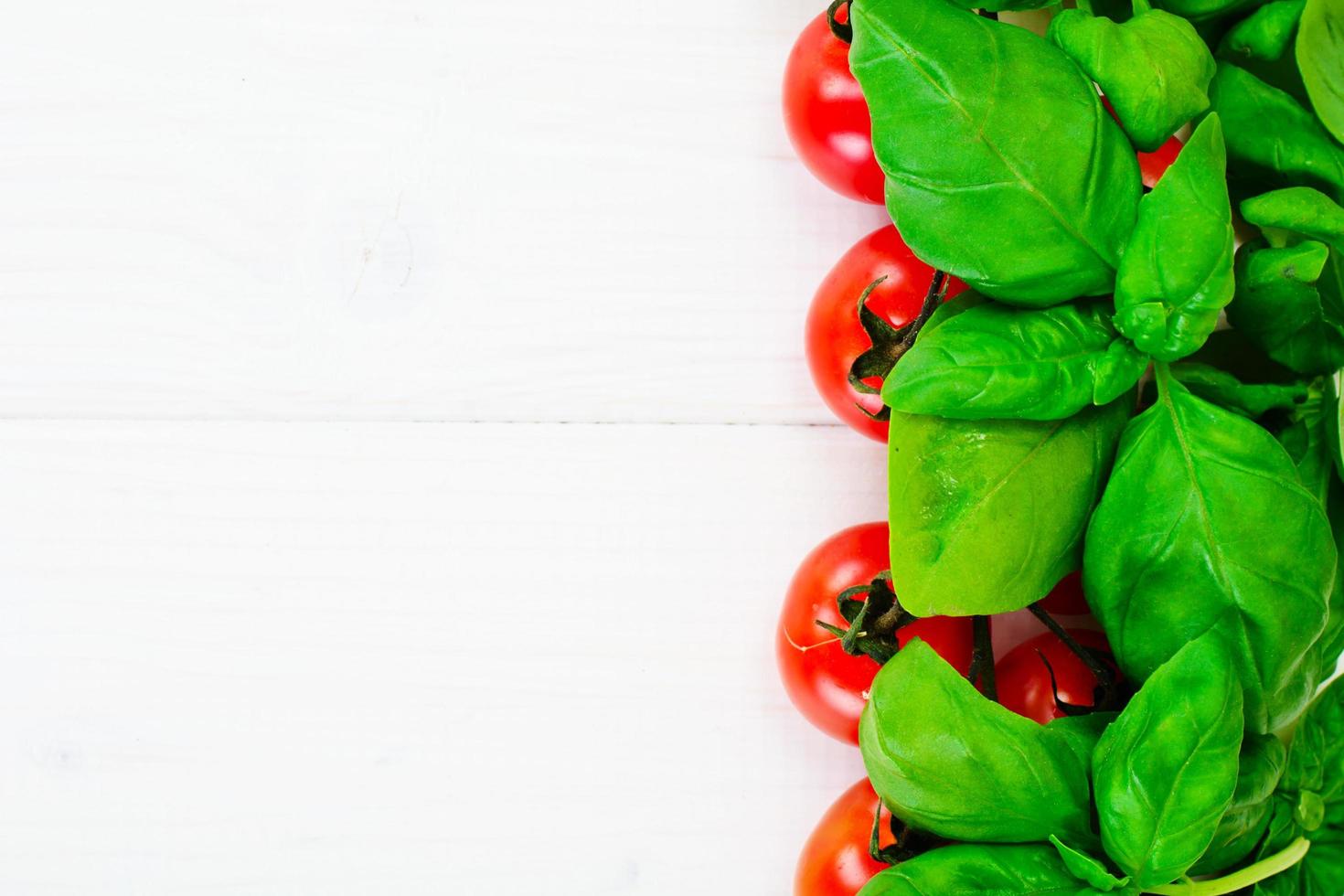 Green Fresh Basil with Tomato on White Woody Board Background photo