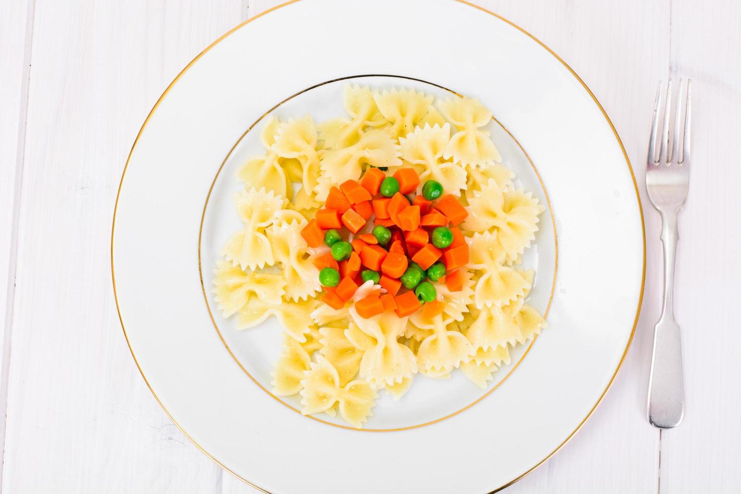 espaguetis de pasta con zanahorias picadas y guisantes verdes foto