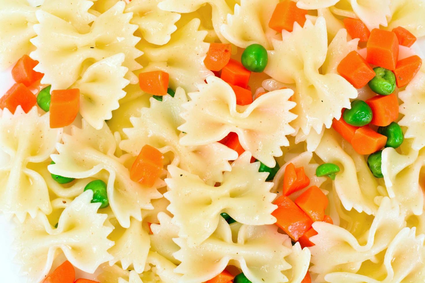 espaguetis de pasta con zanahorias picadas y guisantes verdes foto