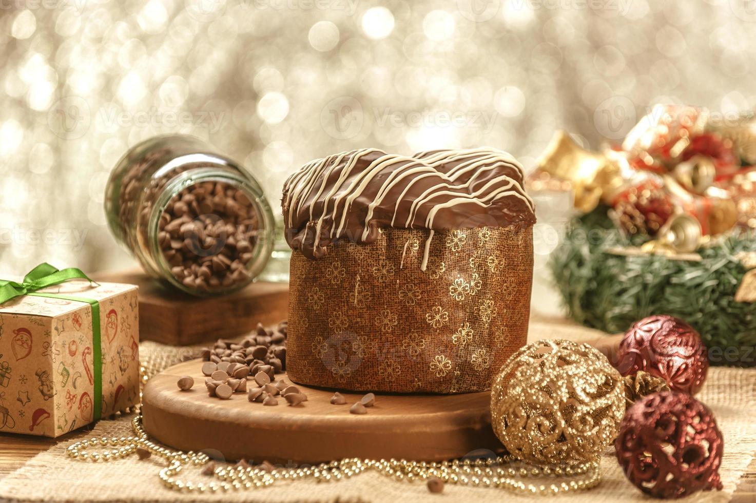 Panettone de chocolate sobre mesa de madera con adornos navideños foto
