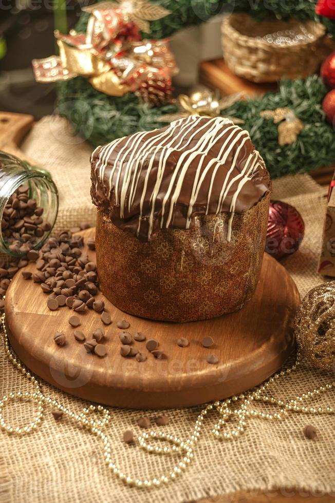 Chocolate panettone  on wooden table with christmas ornaments photo