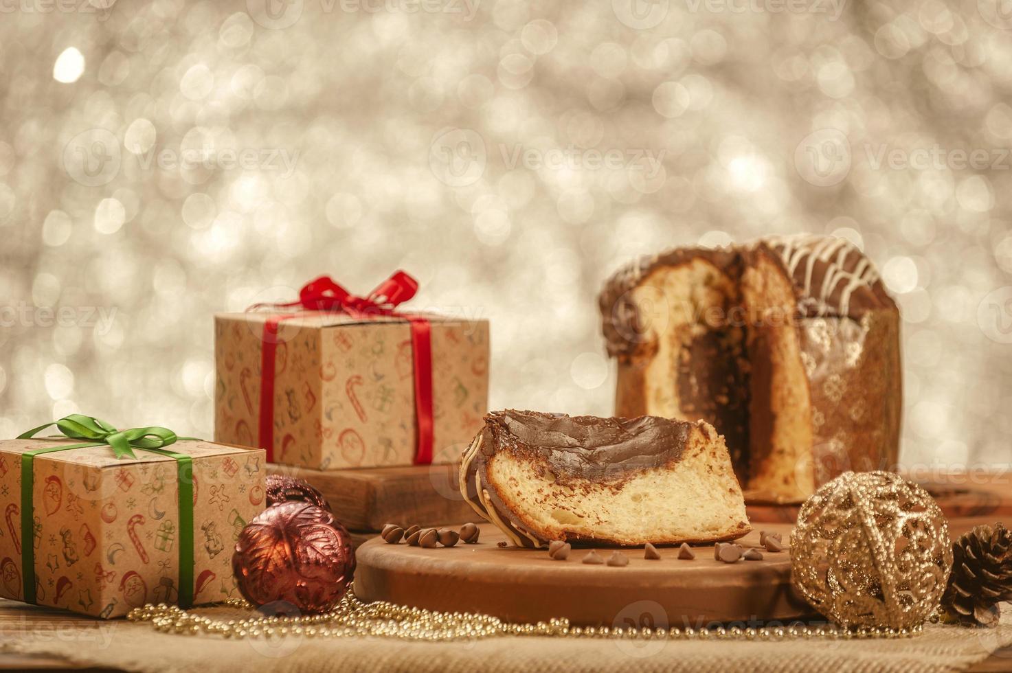 Slice of chocolate panettone  on wooden cutting board with christmas ornaments photo