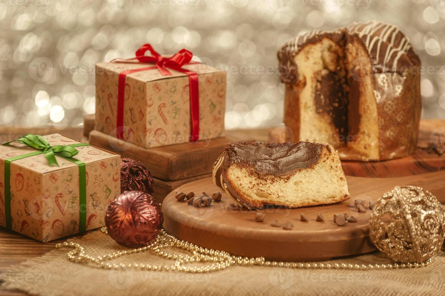 Slice of chocolate panettone  on wooden cutting board with christmas ornaments photo