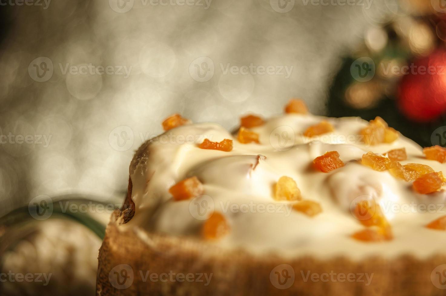 Panettone de chocolate blanco con albaricoque seco sobre mesa de madera con adornos navideños foto