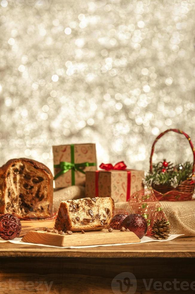 Slice of chocolate panettone  on wooden cutting board with christmas ornaments photo