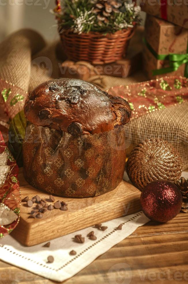 Chocolate panettone  on wooden table with christmas ornaments photo