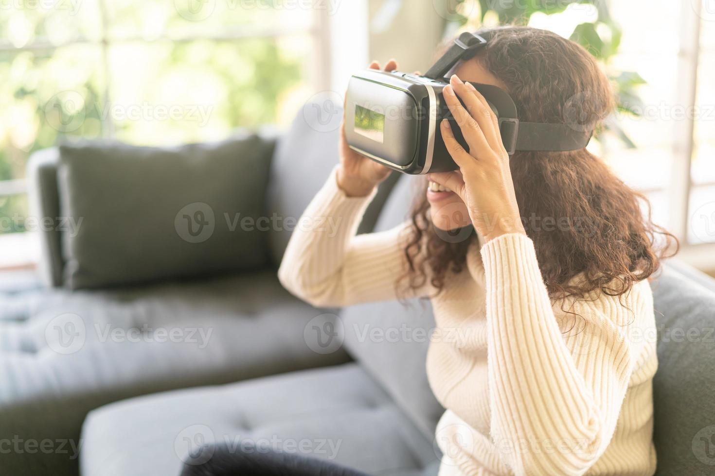 Mujer latina con un casco de realidad virtual en el sofá foto