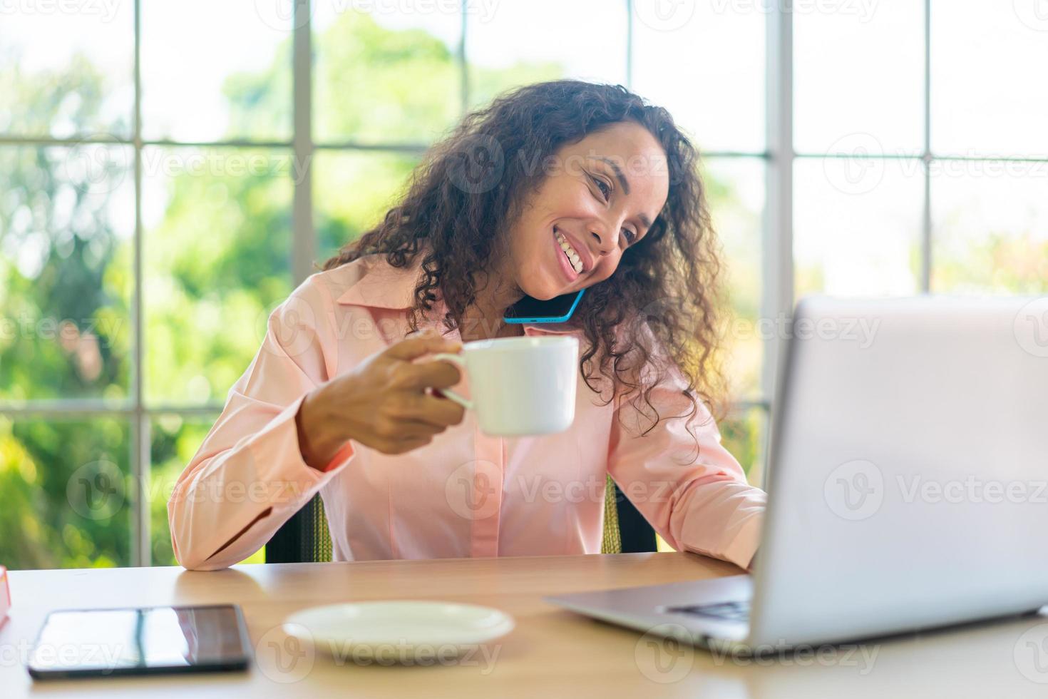 Latin woman working with coffee cup on working space photo