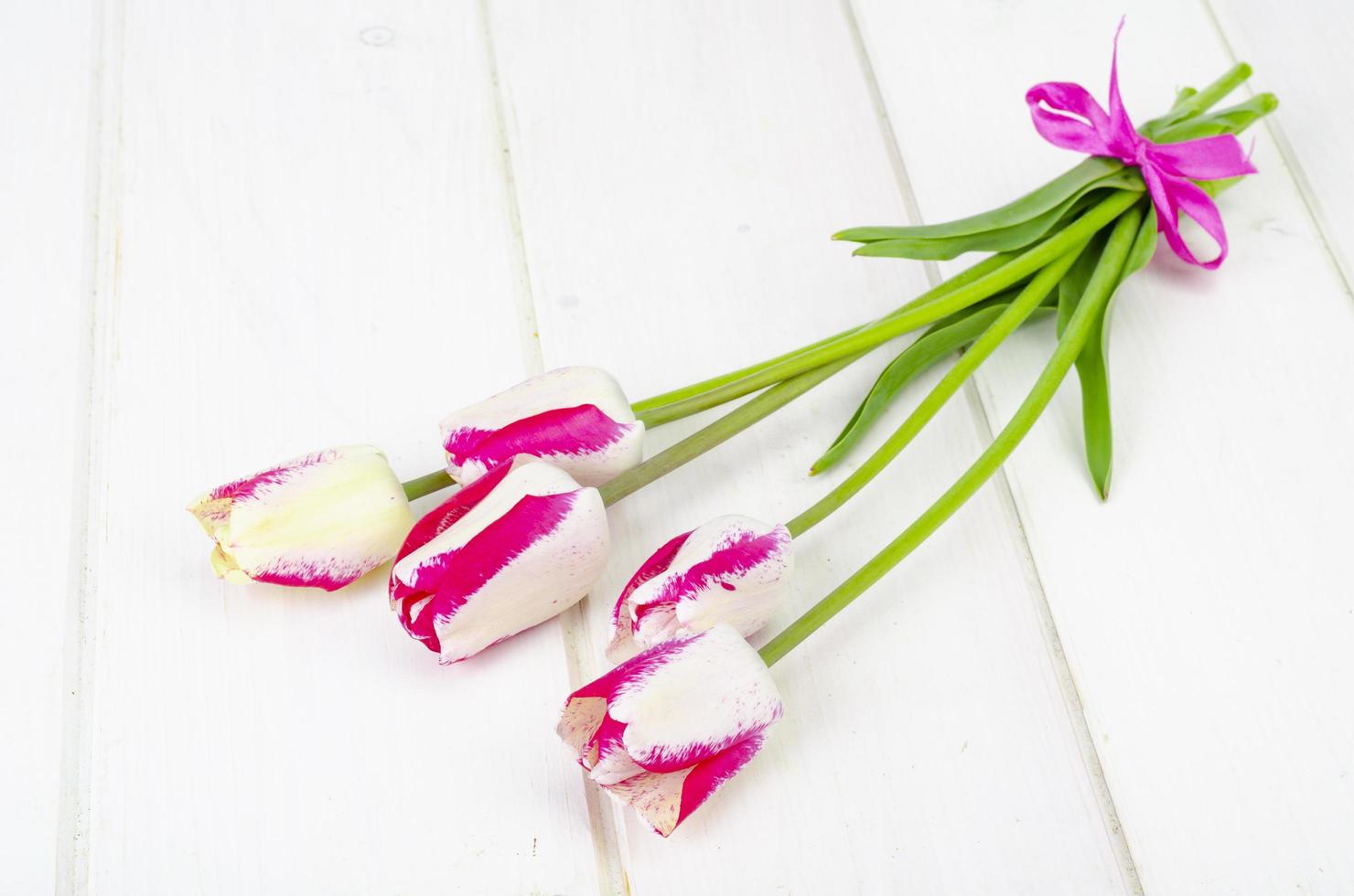 Fresh garden multicolored tulips on white wooden table photo