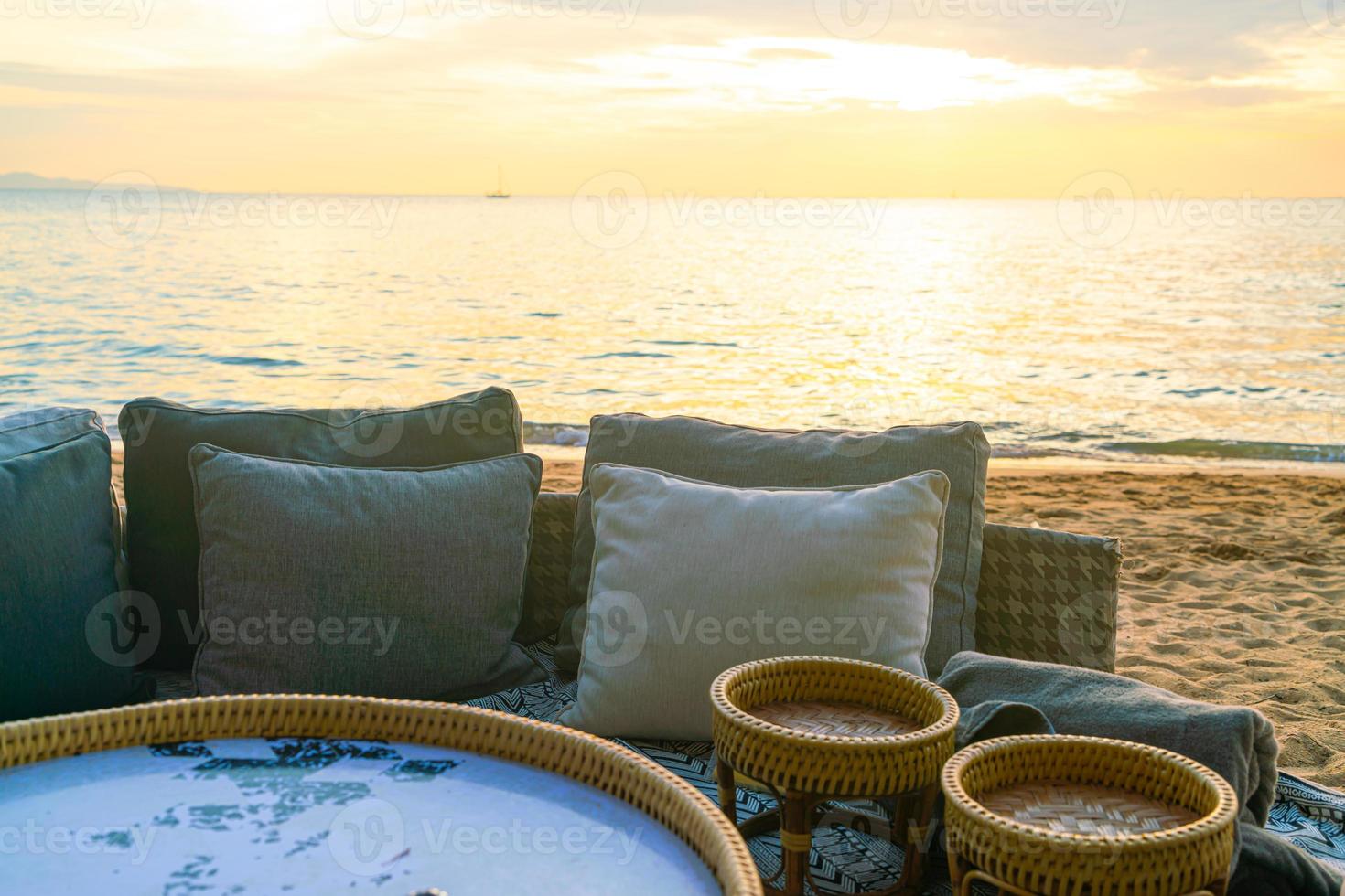Almohadas en la tumbona del patio al aire libre en la playa con la hora del atardecer foto
