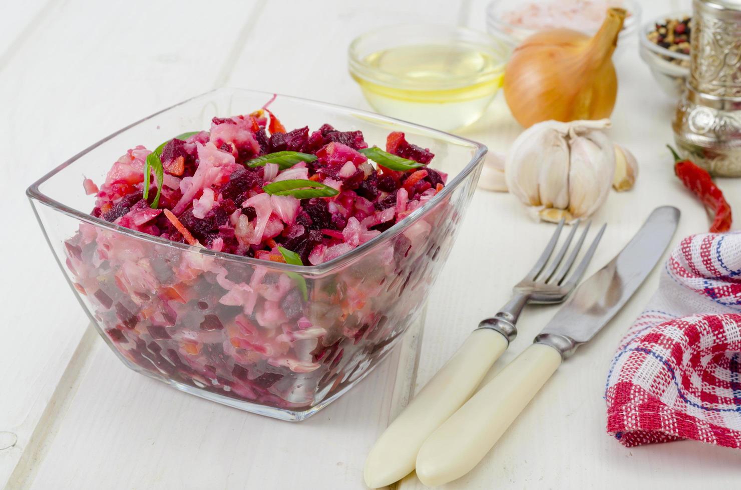 Ensalada de verduras con remolacha, especias, cebollas, ajo en la mesa de madera foto