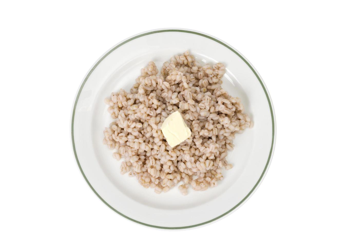 Porridge, boiled pearl barley on plate on white background photo