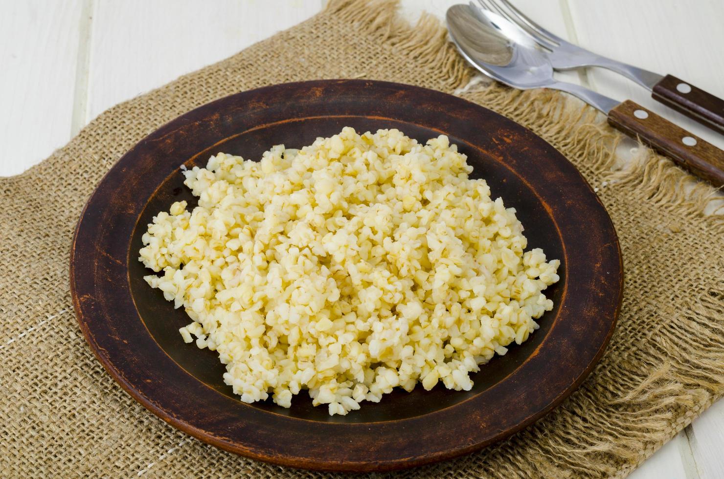 Boiled bulgur groats, vegetarian porridgeon plate. Studio Photo