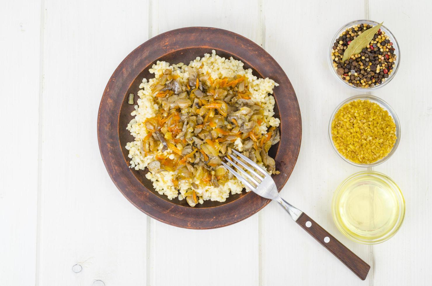Boiled bulgur groats with stewed vegetables and mushrooms, vegetarian food. photo