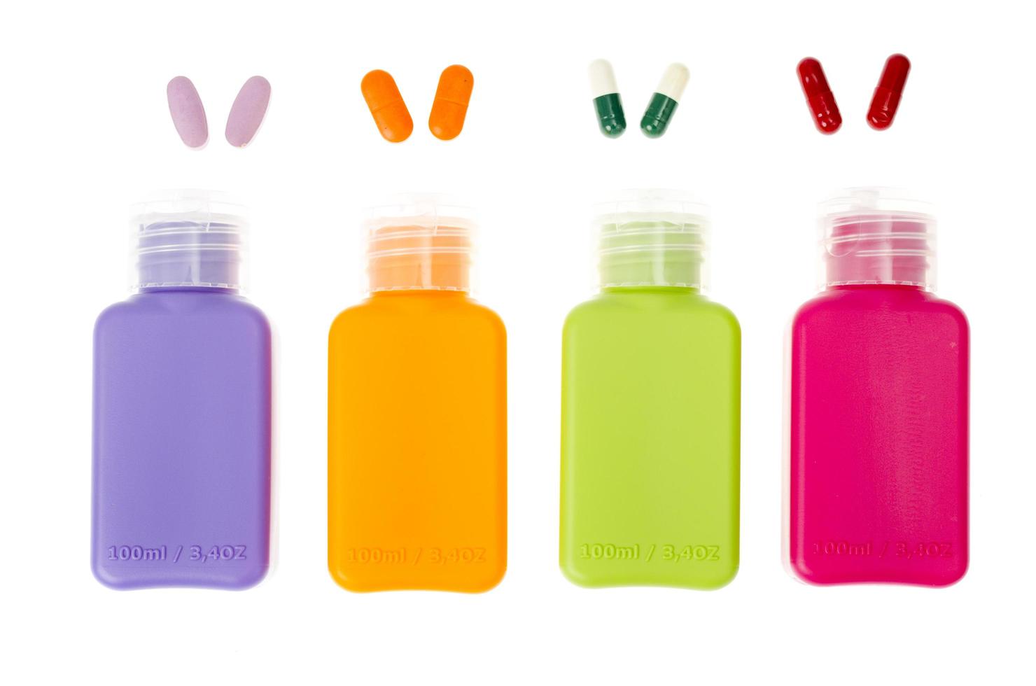 Botellas de plástico multicolores, recipientes con píldoras y cápsulas aisladas sobre fondo blanco. foto