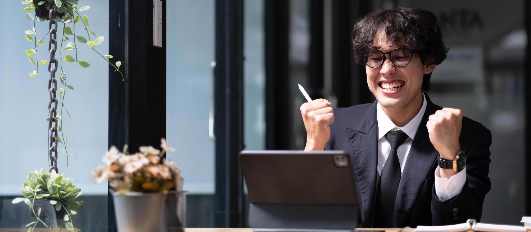 A successful young businessman receives an excited email from his business partner for confirmation. photo