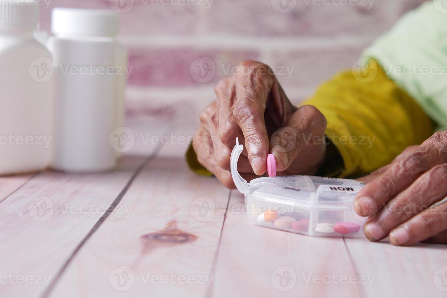 senior women hands taking medicine from a pill box photo