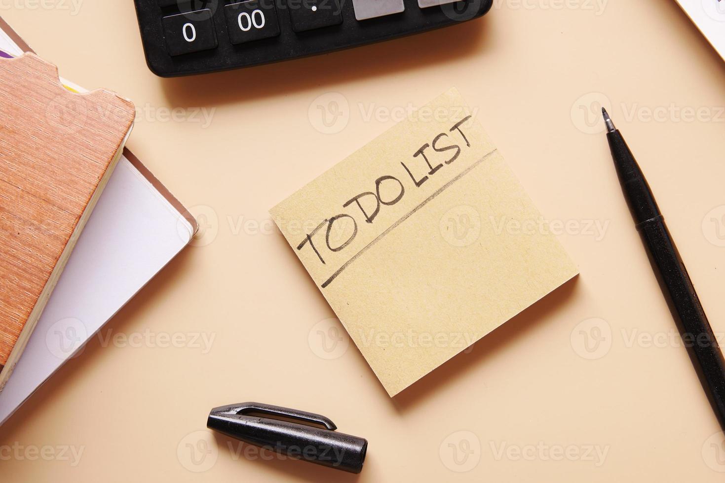 To do list in notebook with office suppliers on desk. photo