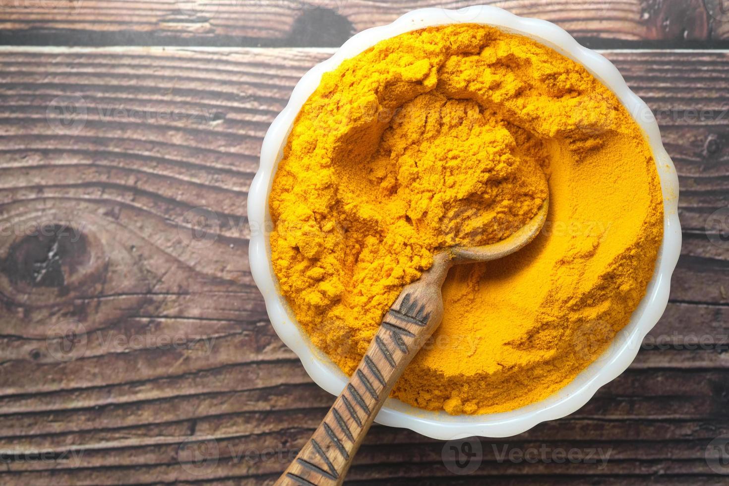 turmeric root powder in bowl on table , photo