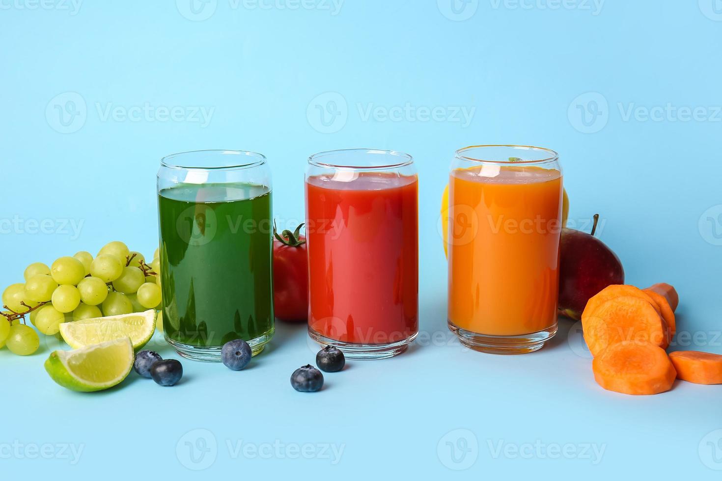 Vasos con jugos saludables, frutas y verduras sobre fondo de color foto