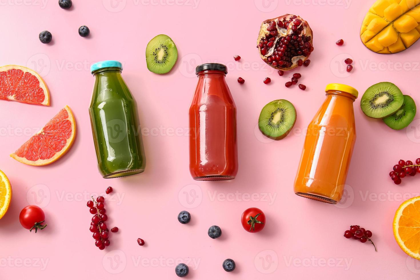 Bottles with healthy juice, fruits and vegetables on color background photo