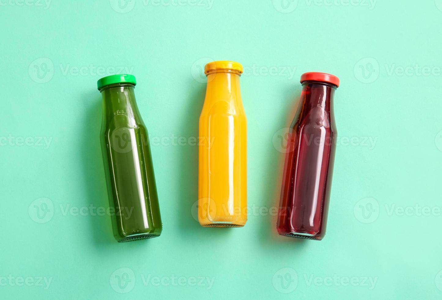 Bottles with healthy juice on color background photo