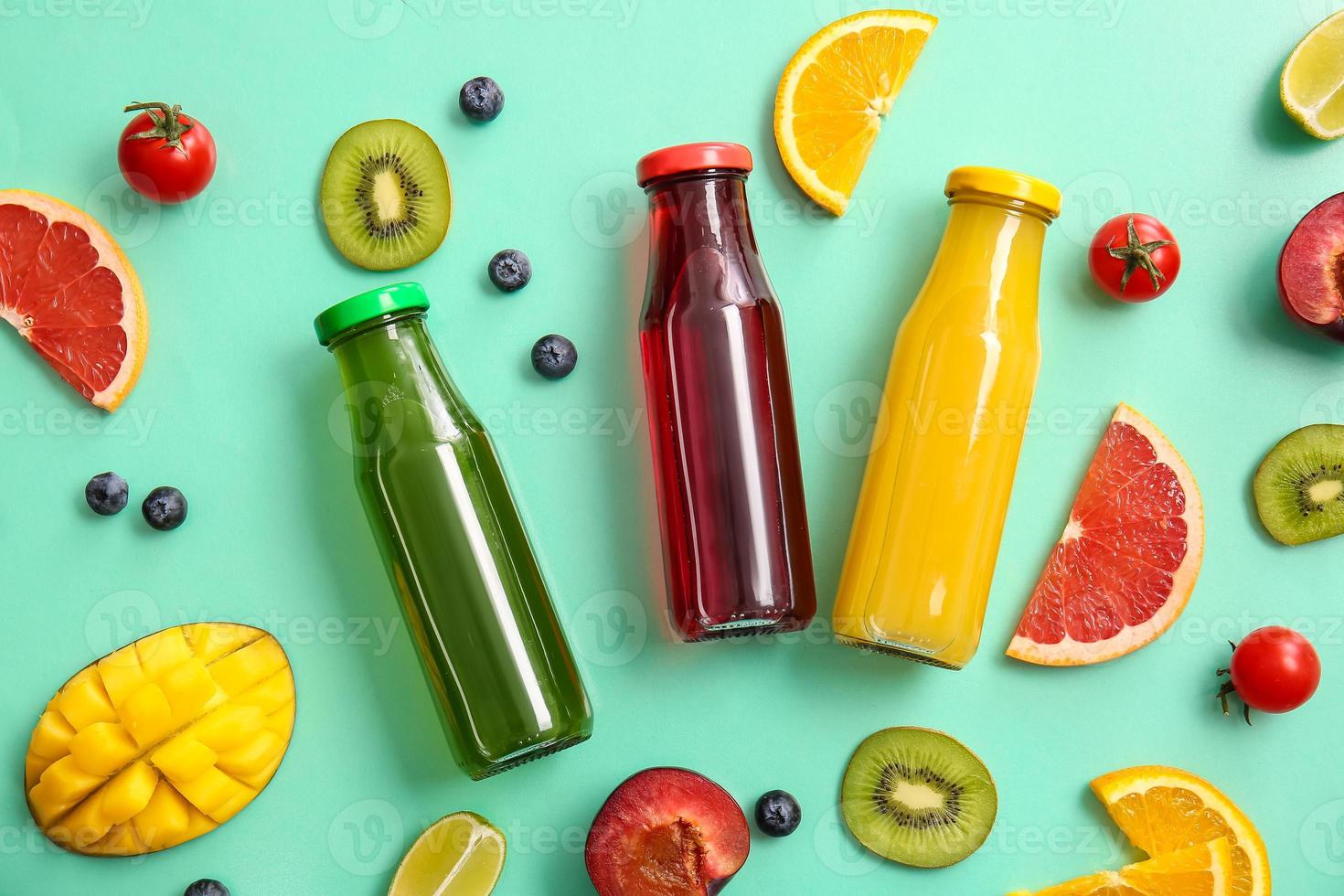 Botellas con jugos saludables, frutas y verduras sobre fondo de color foto