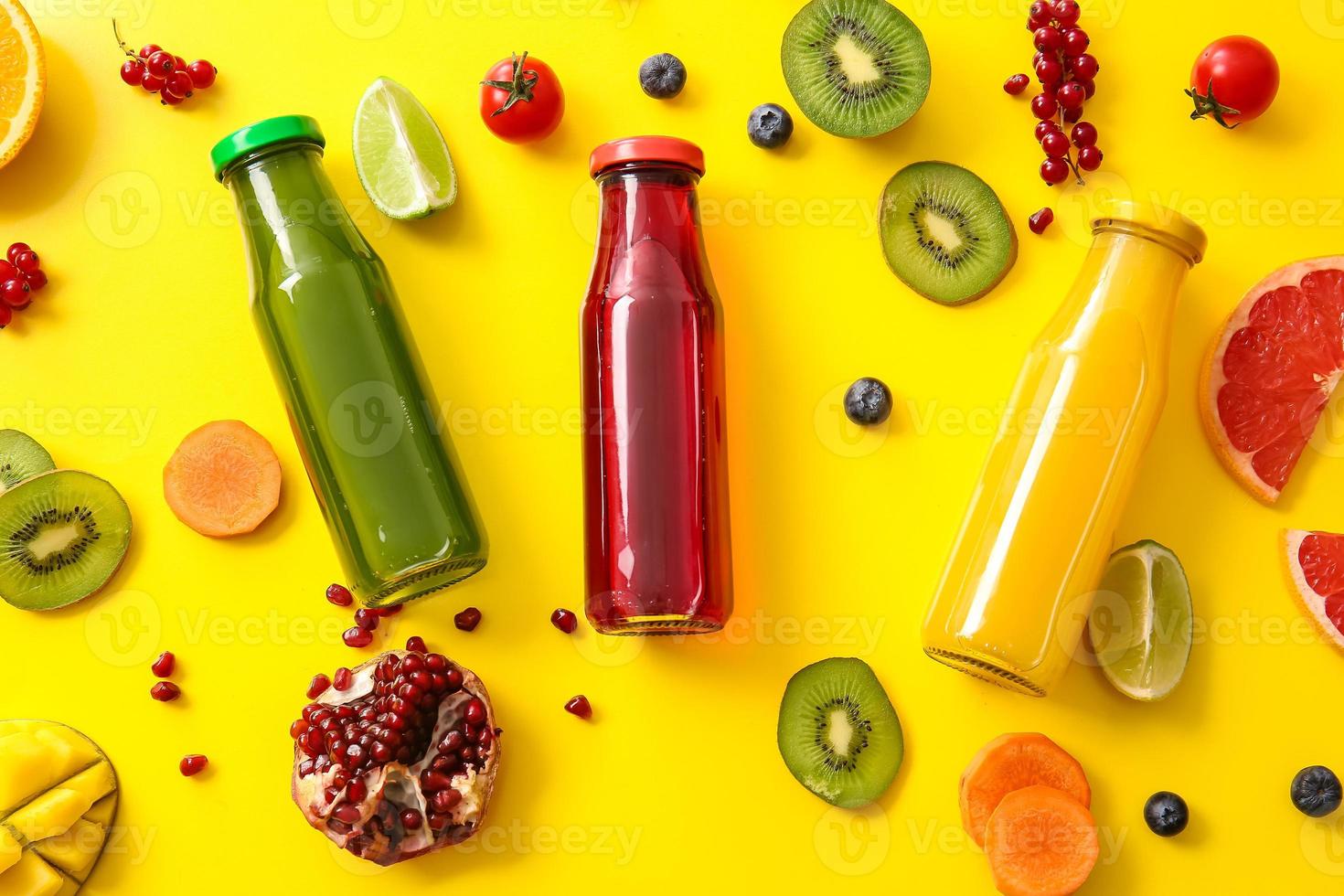 Botellas con jugos saludables, frutas y verduras sobre fondo de color foto