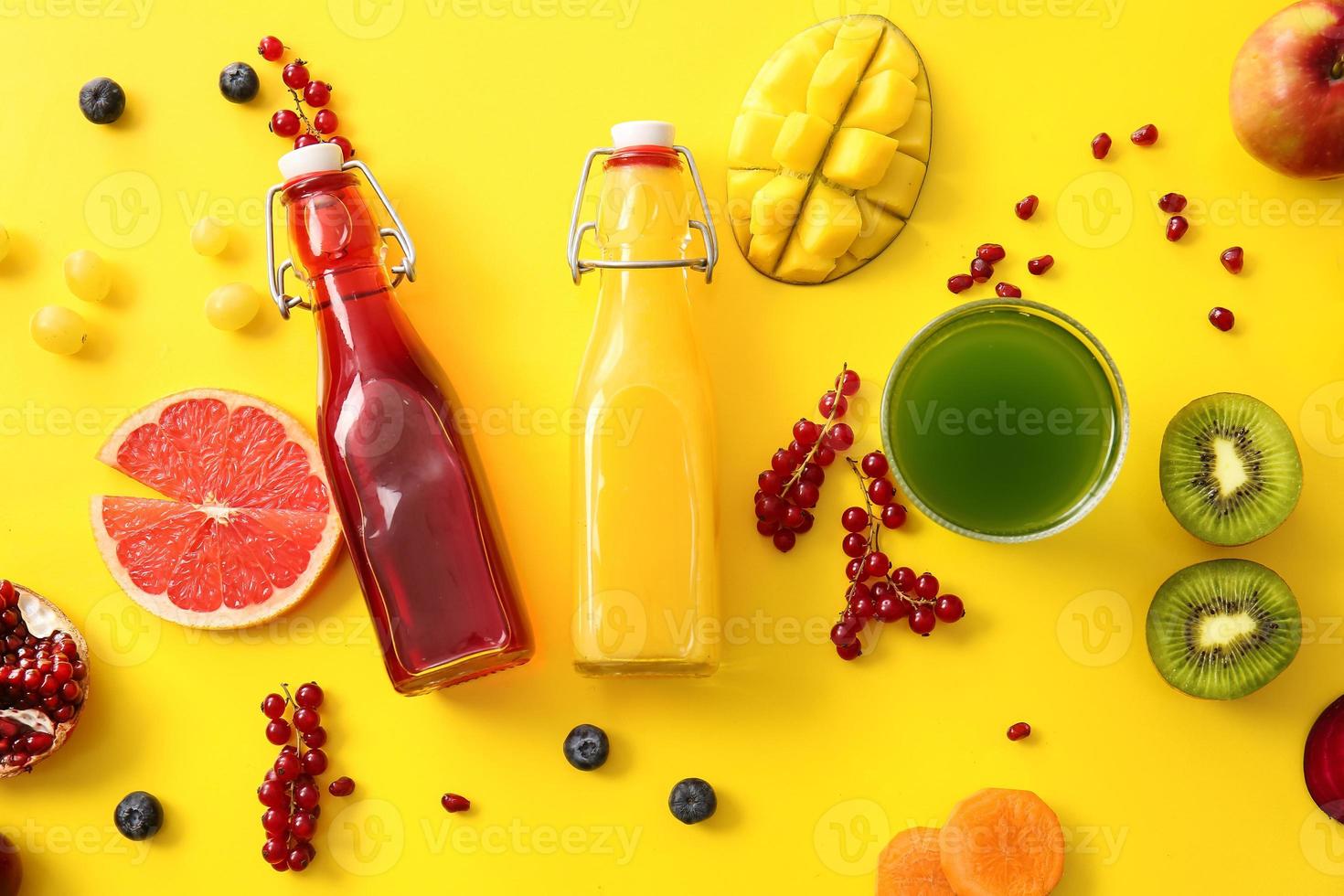 Bottles with healthy juice and fruits on color background photo