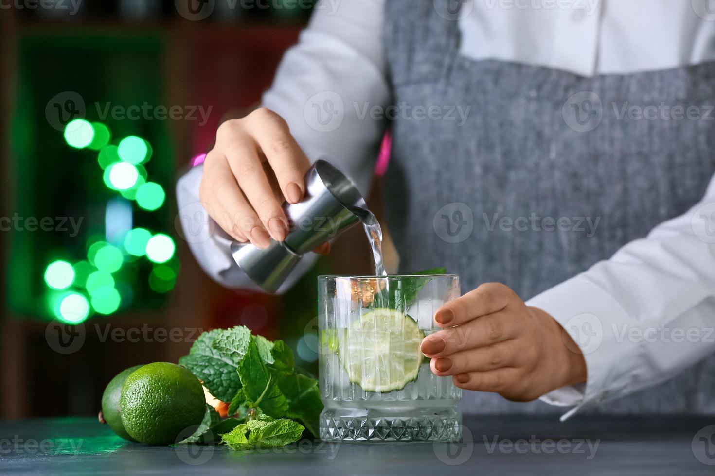 Camarero haciendo mojito fresco en la mesa en el bar foto